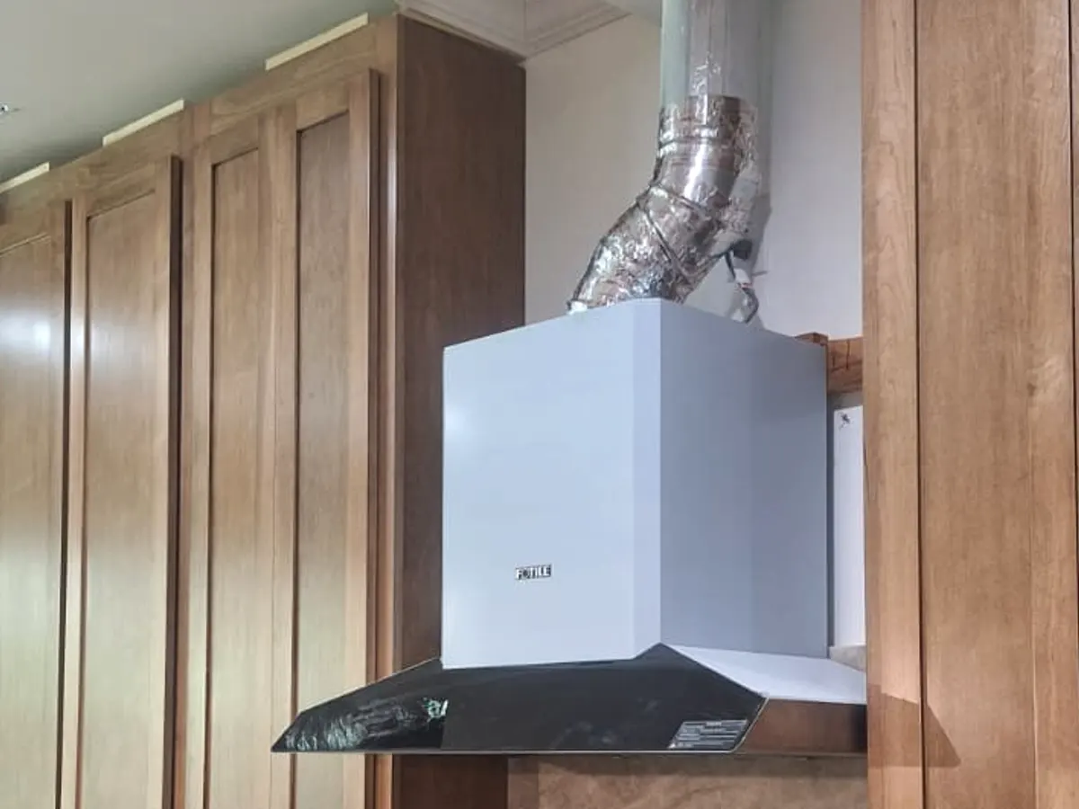 Stainless range hood vented through a wrapped duct in a custom kitchen